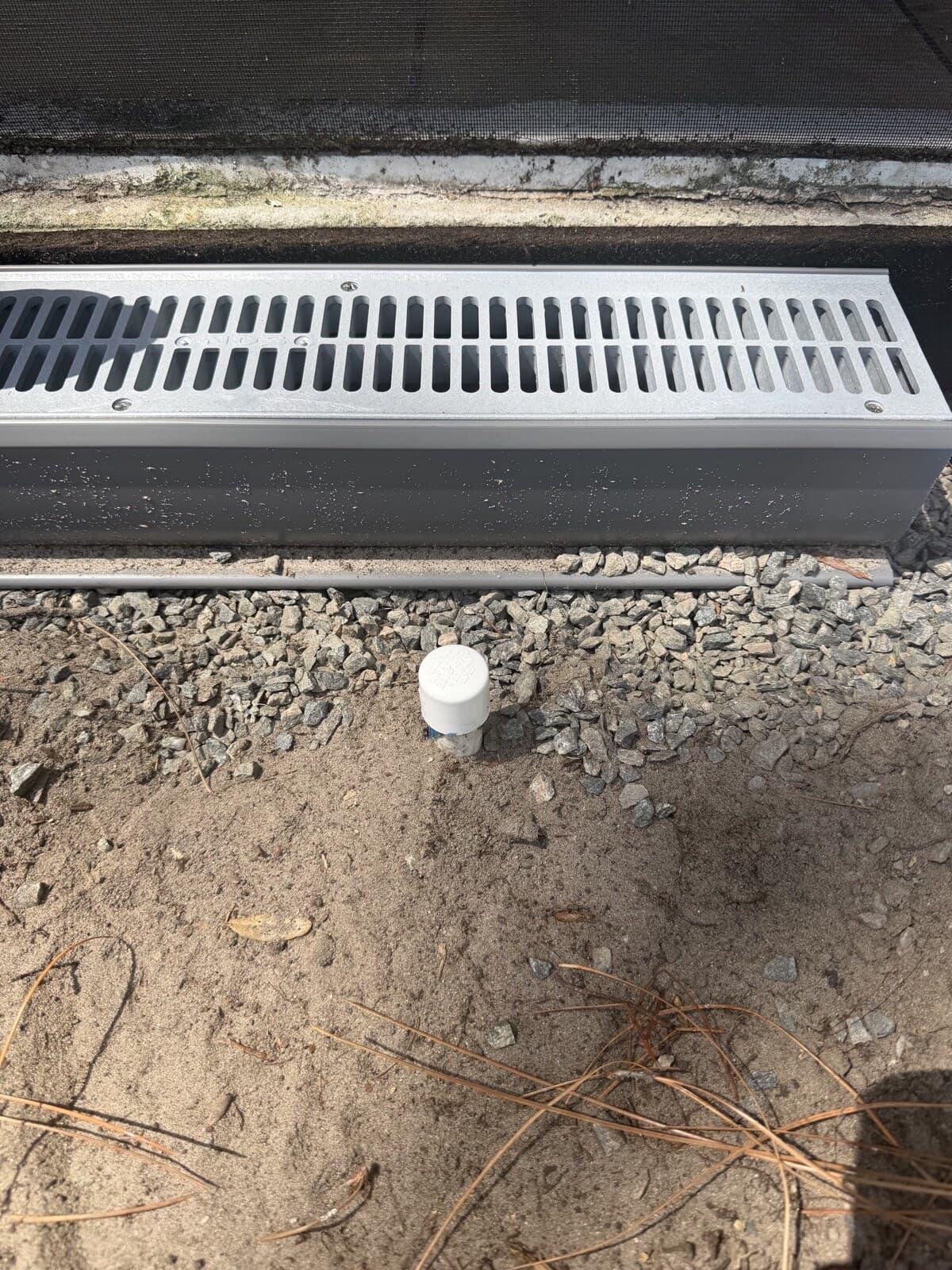 Channel drain installed in gravel with cleanout at a Central Florida property
