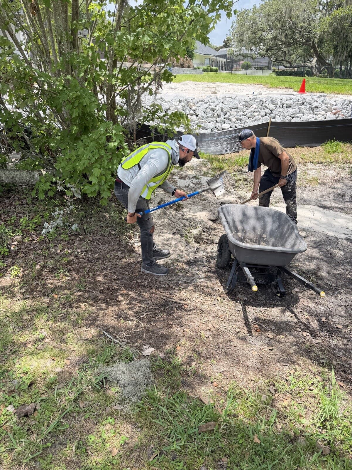 LES crew placing riprap at a lawn edge with an erosion barrier at a Central Florida site